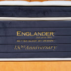 Stack of mattresses with 'Englander' branding and '130th Anniversary' text on a wooden floor.