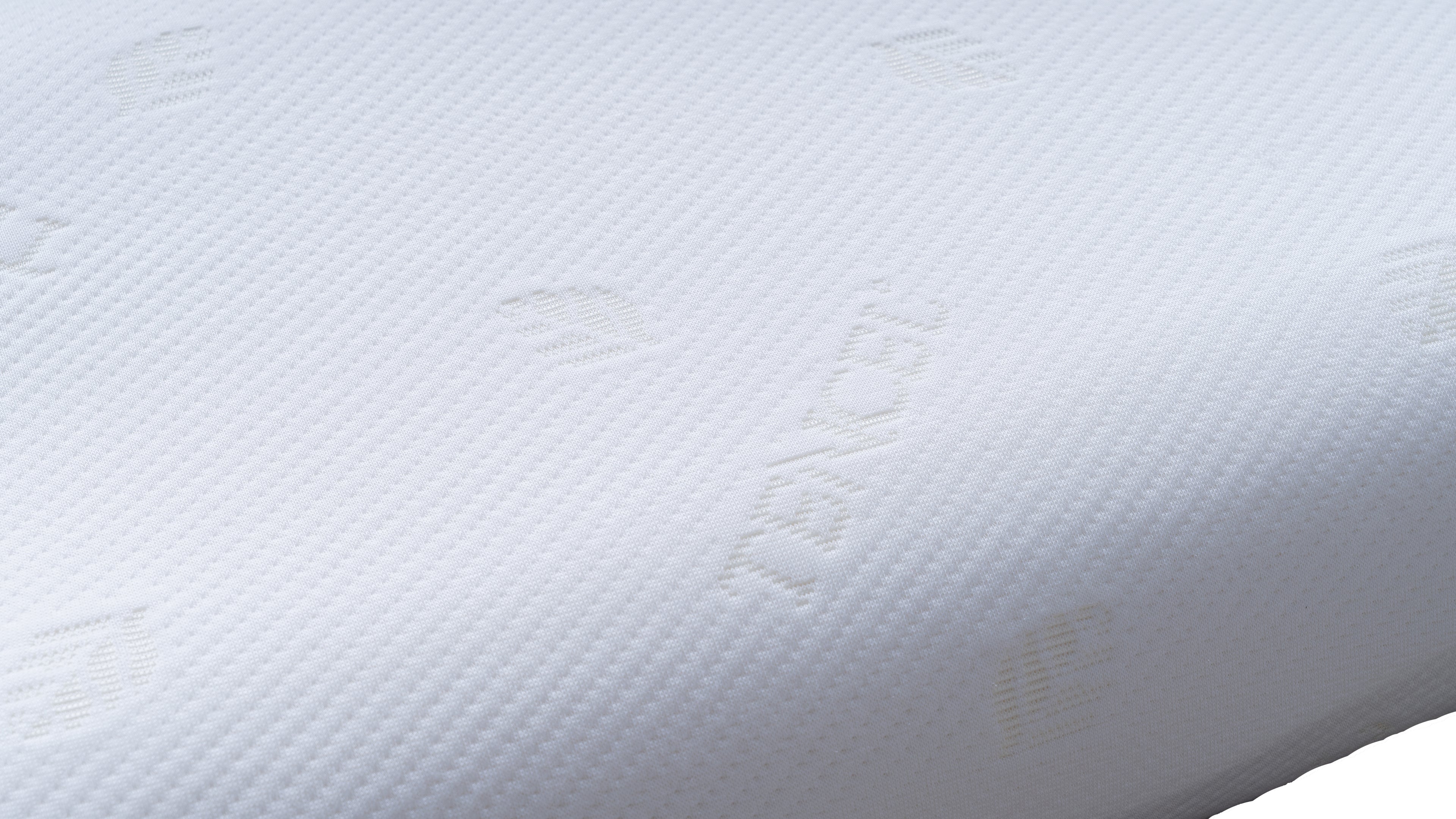 Close-up of a white textured pillow surface with subtle embossed branding and a dimpled fabric pattern.