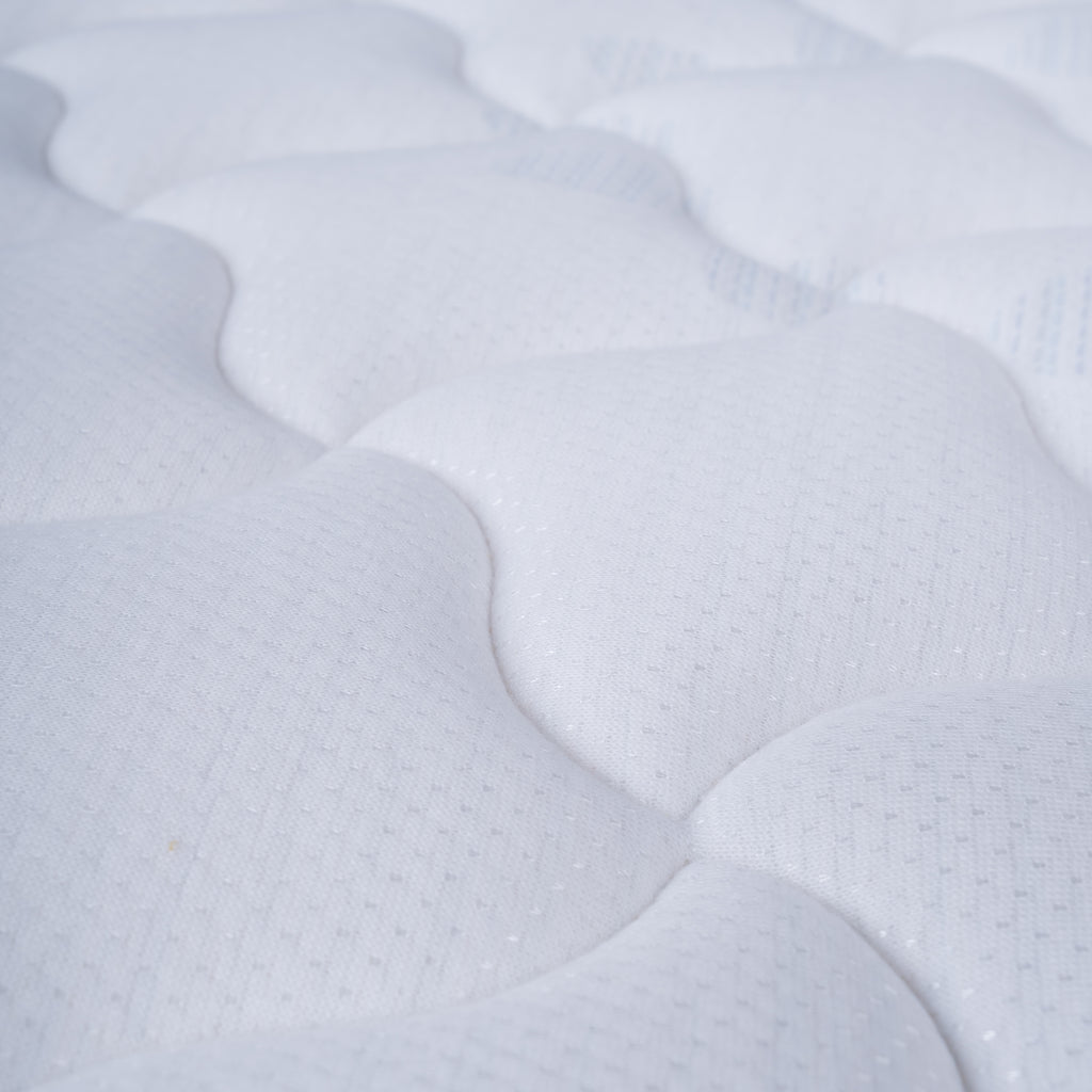 Close-up of a white quilted Englanders Spinal Classic mattress or cushion surface with a wavy stitched pattern and subtle texture.