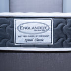Close-up of an Englander Spinal Classic mattress showing the brand label on the side, with dark gray quilted padding and a white border.