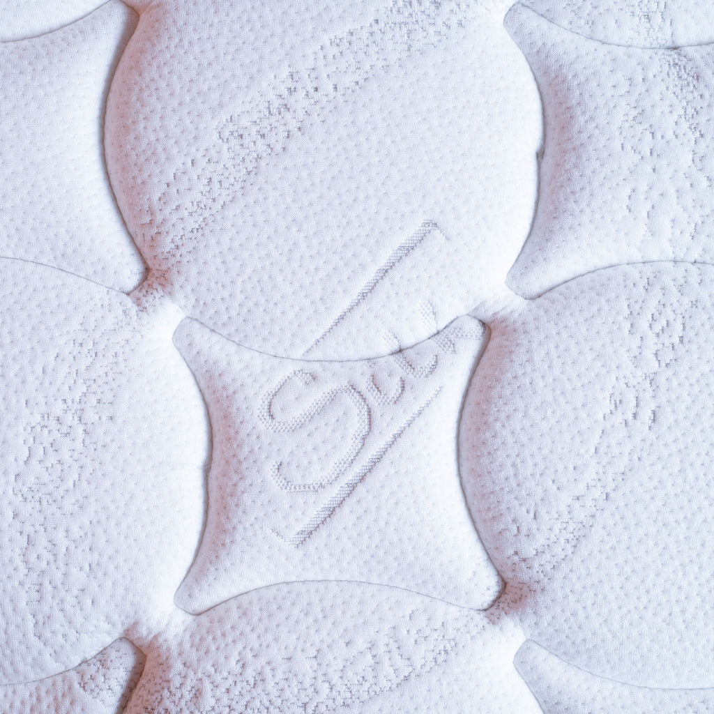 Close-up of mattress surface with brand logo on a light background