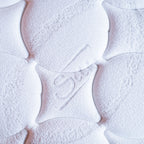 Close-up of mattress surface with brand logo on a light background