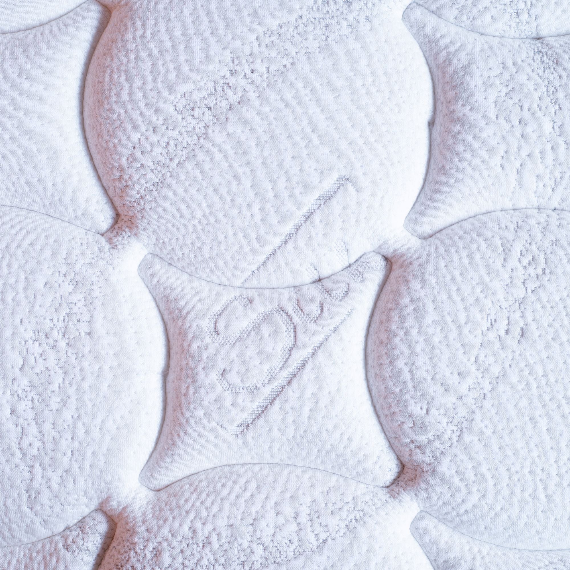 Close-up of mattress surface with brand logo on a light background