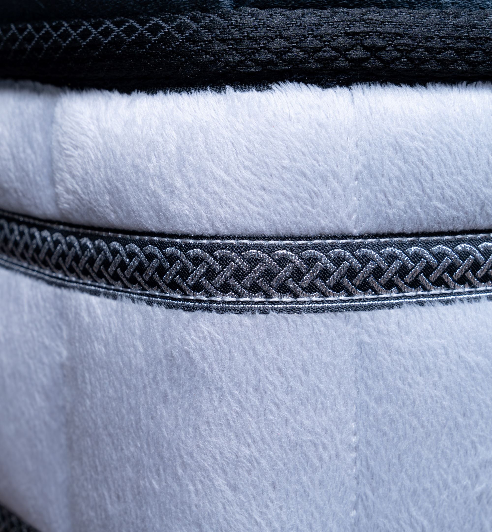 Close-up of a textured fabric with braided trim on a white background